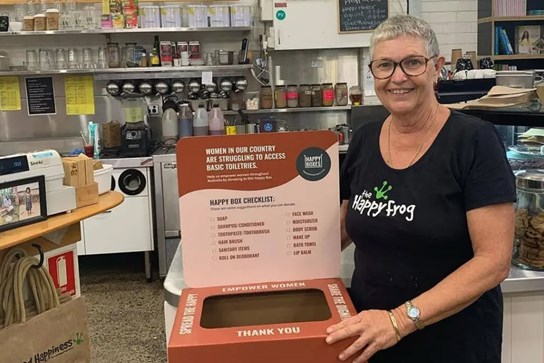 Happy Frog Cafe's Kim Towner next to a donation box for a women's charity. One of her many ongoing projects!