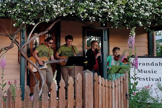 A family band of four perform on a cottage verandah, surrounded by beautiful spring flowers